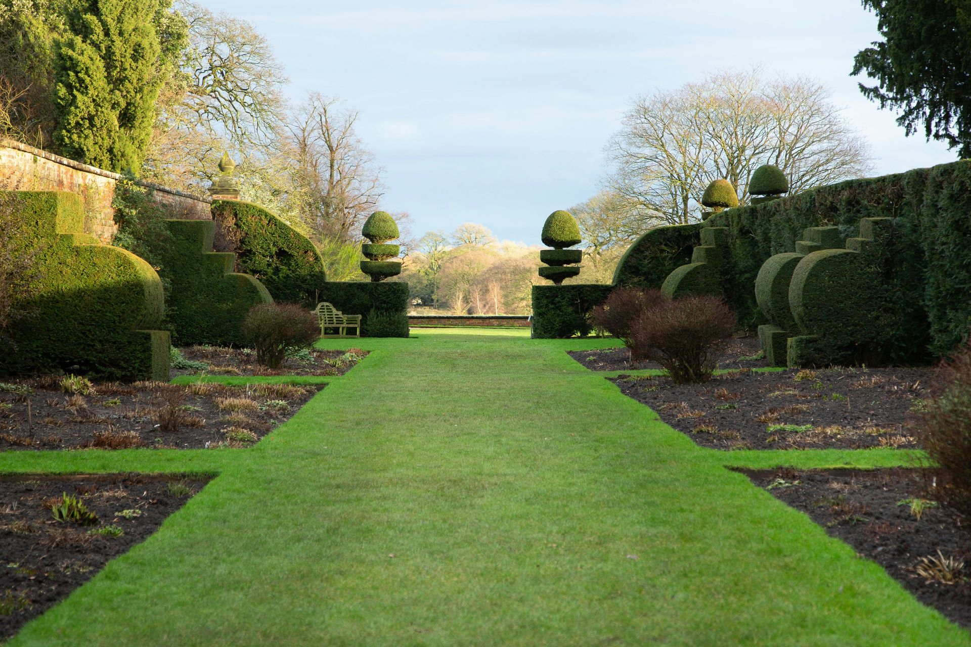 a long green lawn lined with trees and bushes